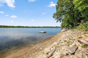 A lakeside view with a dock, rocky shoreline, and a tree-lined area. - Sunset Cabin 4-bedroom cabin in adorable Dassel perfect for relaxing getaways (Dassel)