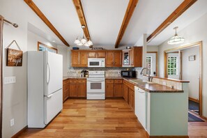 Une cuisine avec des meubles en bois, un réfrigérateur blanc, un four à micro-ondes et une cuisinière.