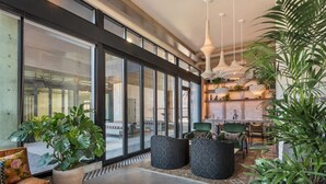 Et moderne interiør med store vinduer, et spiseområde og flere krukkeplanter.
