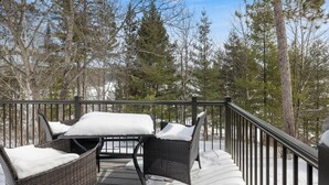 Una terraza con mobiliario de mimbre y suelo cubierto de nieve.