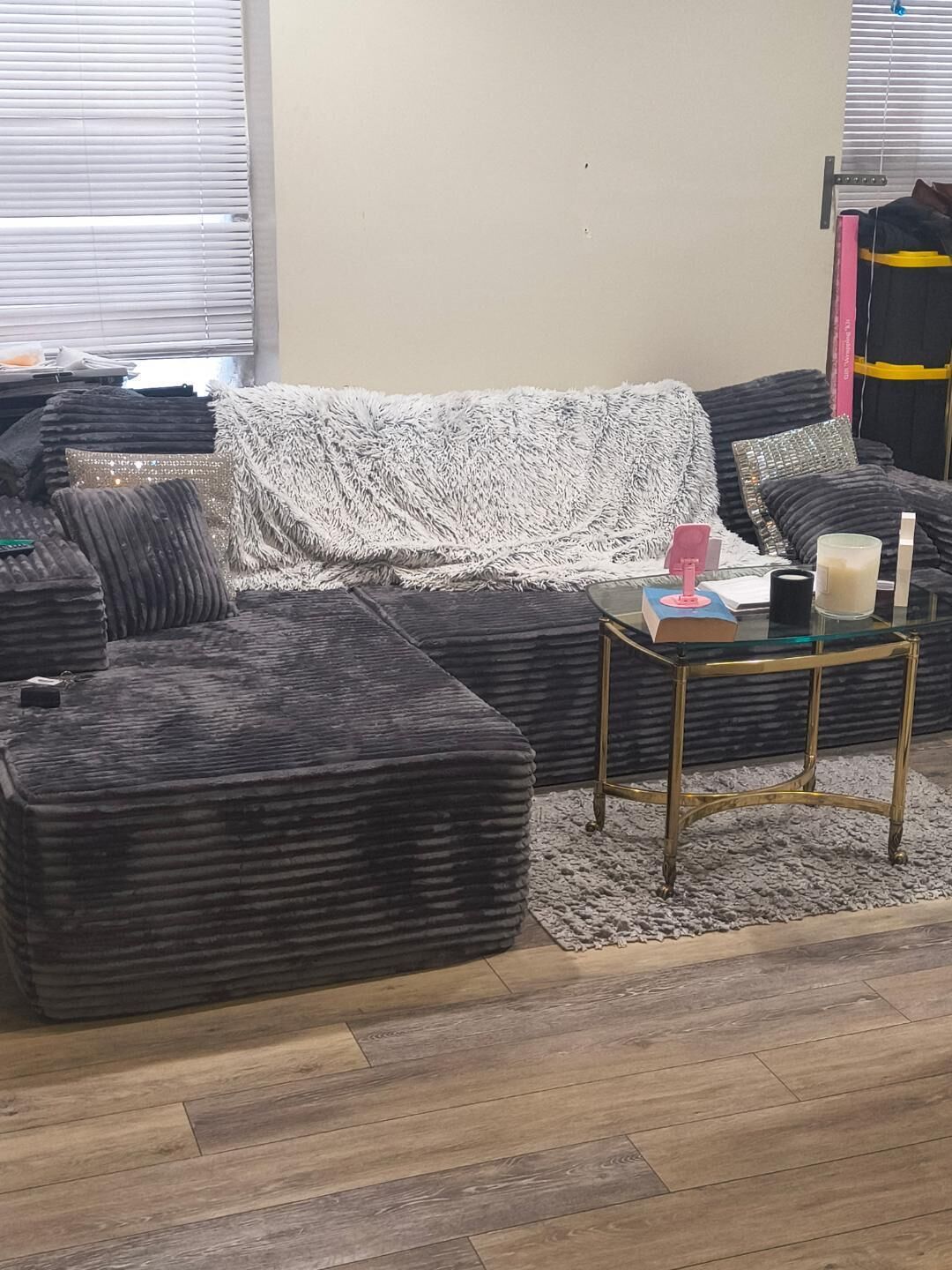 A living room with a sectional sofa, a glass coffee table, and a rug.
