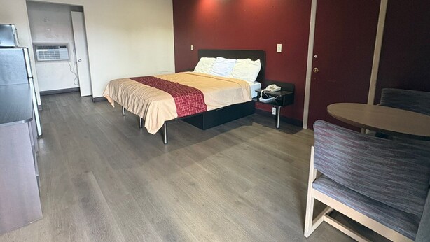 Une chambre d’hôtel comprenant un lit, une petite table, une chaise, un bureau et une kitchenette.