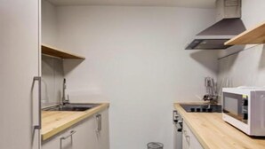 Una cocina estrecha con armarios blancos, encimera de madera, microondas y un fregadero.
