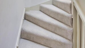 Una escalera con barandilla, una pared con letrero de salida verde y un cuadro enmarco.