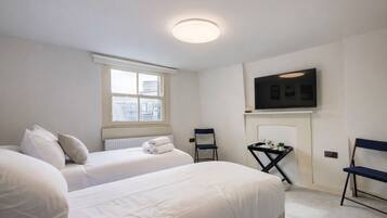 A hotel room with two beds, a TV, a chair, a small table, and a window with a view.