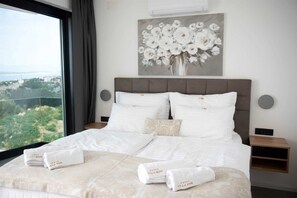 A hotel room with a bed, pillows, a vase of flowers on the wall, and towels on the bed.