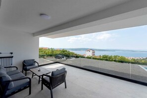 A balcony with a view of a body of water and distant buildings.
