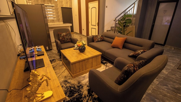 A modern living room with a sofa, coffee table, and a TV on a wooden stand. - NimbusNiche Luxury Residence (Akaikrom)