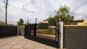 A gated area with a tiled floor, a brick wall, and a building in the background. - NimbusNiche Luxury Residence (Akaikrom)