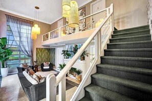 A spacious living area with a staircase leading to an upper level. - Renovated Studio | Walk to Downtown Lake Worth (Lake Worth Beach)