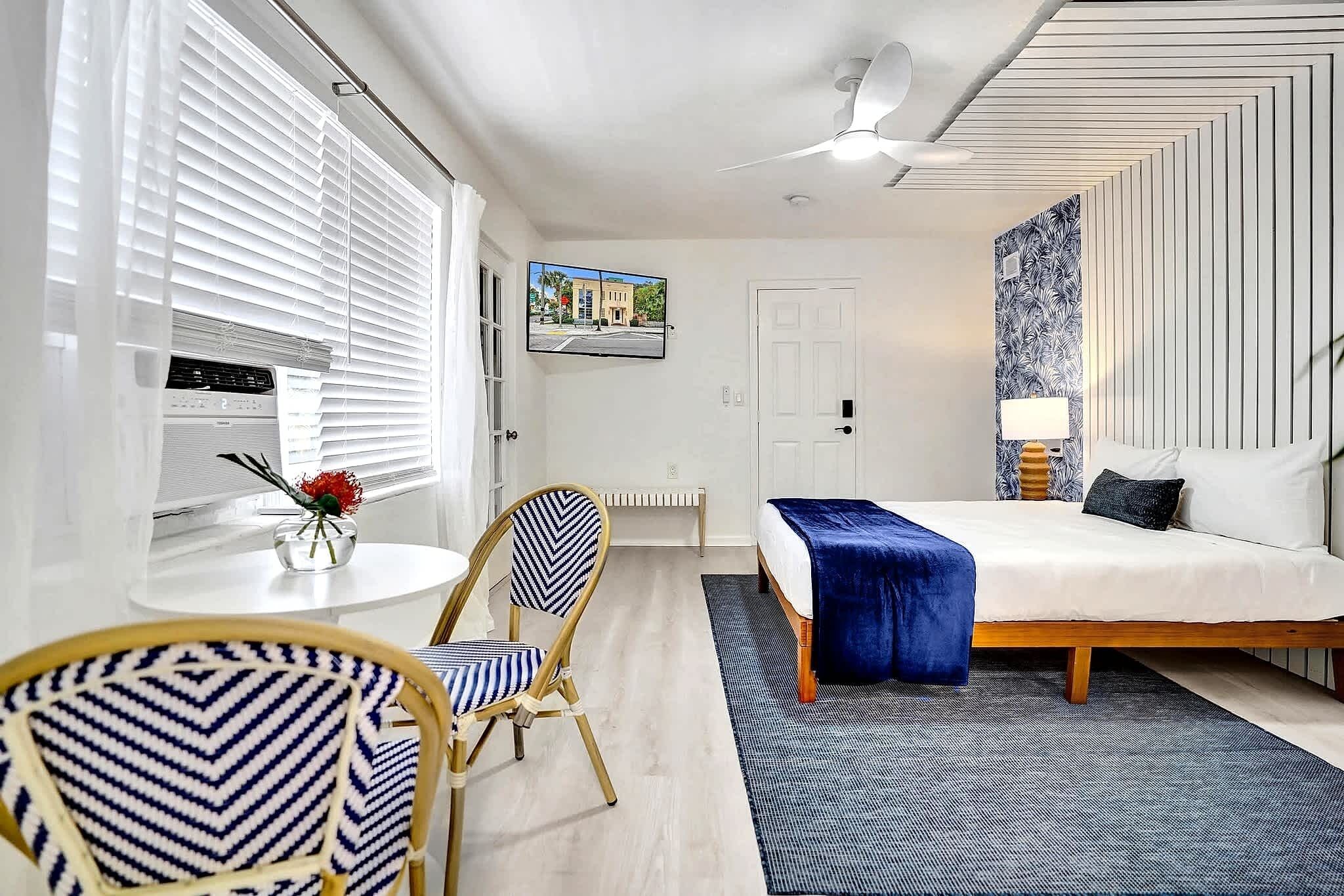Una camera d'albergo moderna con un letto, una scrivania, una sedia, un termosifone e una TV a parete.