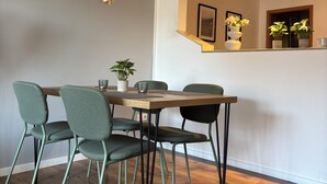 En matplats med ett träbord, fyra stolar och hängande taklampor.