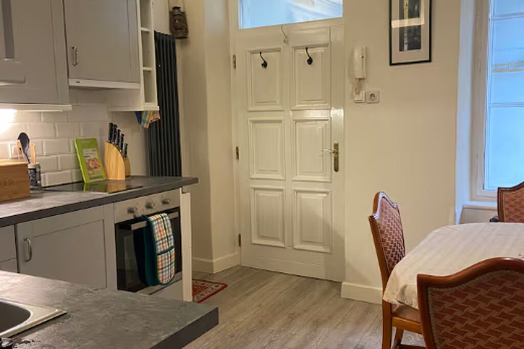 A kitchen with a built-in oven, a dining table with chairs, a white door, and a window.