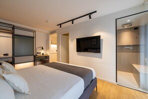 A modern hotel room with a bed, a desk, a TV, and a glass partition. - Hotel Piccadilly (Riccione)