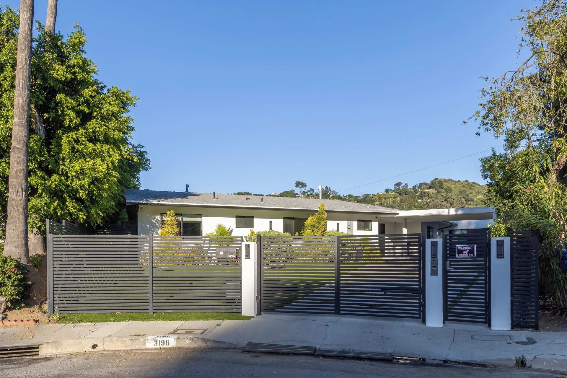 A gated entrance to a modern building with a flat roof and a visible garage door.