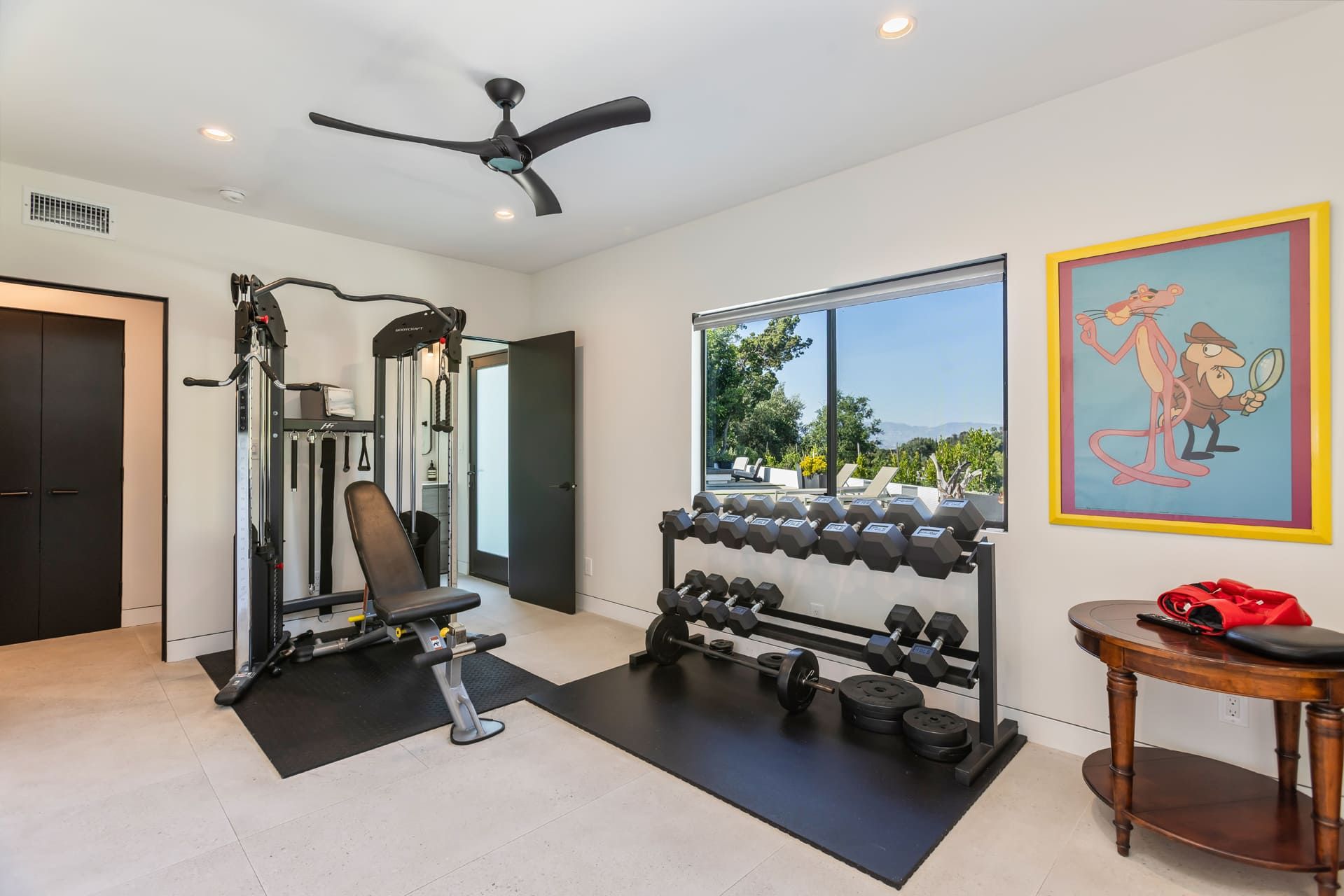 A home gym with exercise equipment, a large window, and a painting.