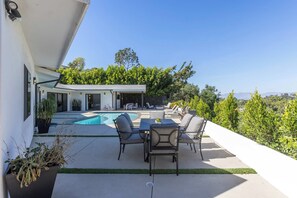 A modern outdoor patio with a pool, seating, and a view of a house and trees. - Casa Dona by Oraklus (Beverly Hills)