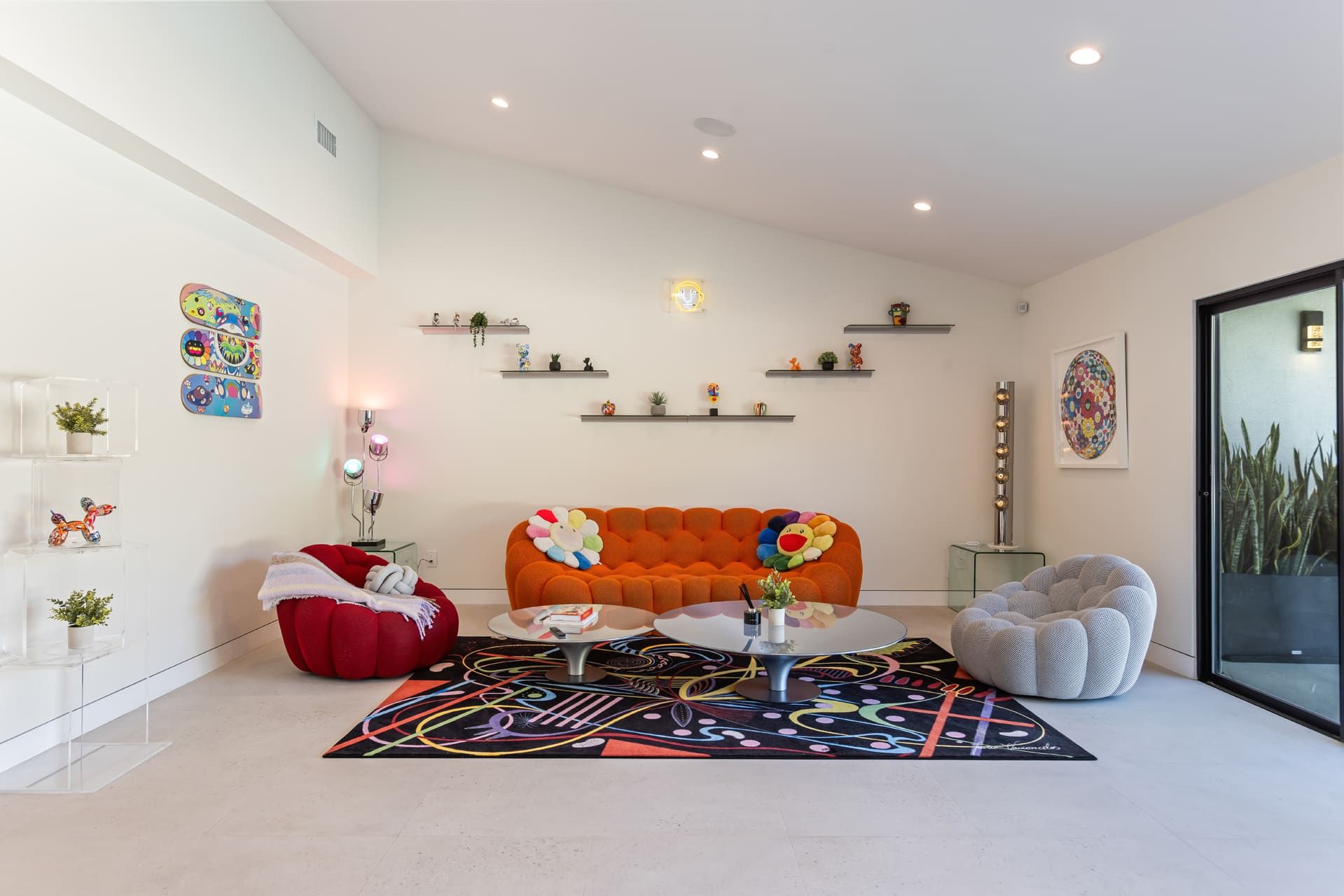 A modern living room with a sofa, red pouf, and a coffee table.