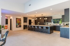 Una cocina moderna con una isla central, taburetes de bar e iluminación colgante.
