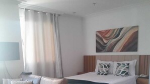 A modern hotel room with a bed, a sofa, and a desk. - Lindo Apto algumas quadras da Paulista (São Paulo)