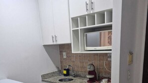 A kitchen with white cabinets, a microwave, a coffee maker, and a refrigerator. - Lindo Apto algumas quadras da Paulista (São Paulo)