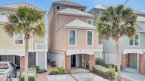 A row of townhouses with a garage, a brick entrance, and palm trees. - 110 Grand Pavilion by Avantstay Direct Access To Grand Pavilion Boardwalk (Isle of Palms)