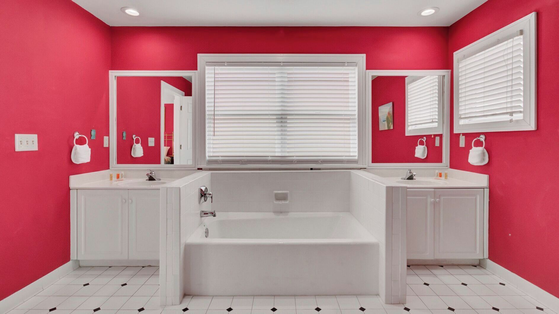 A bathroom with a large bathtub, two sinks, and a mirror above the bathtub.