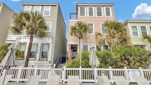 A row of multi-story buildings with balconies, palm trees, and a white fence with lounge chairs. - 110 Grand Pavilion by Avantstay Direct Access To Grand Pavilion Boardwalk (Isle of Palms)