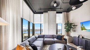 Een moderne woonkamer met een modulaire bank, een ronde salontafel en een groot raam met uitzicht op de stad.