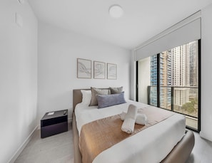 A modern hotel room with a large bed, a bedside table, a small desk, and a window with a city view. - Sleek 1-BR & Den in Miami Central - Rooftop Pool (Miami)