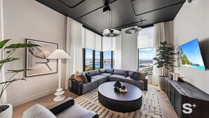 Ein modernes Wohnzimmer mit einer Eckcouch, einem runden Couchtisch und einem großen Flachbildfernseher.