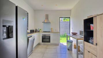 Une cuisine moderne équipée d’appareils électroménagers en acier inoxydable, d’un lave-vaisselle et de meubles de rangement en bois.