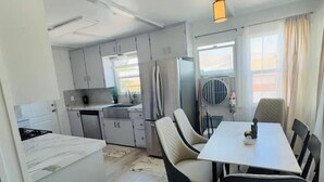 A compact kitchen with modern appliances, a dining area with a table and chairs, and a view through a window. - Charming house in pleasant Yucca Valley (Yucca Valley)