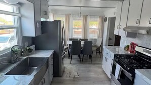 A modern kitchen with a dining area, stainless steel appliances, and a marble backsplash. - Charming house in pleasant Yucca Valley (Yucca Valley)