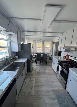 A modern kitchen with a dining area, stainless steel appliances, and a marble backsplash. - Charming house in pleasant Yucca Valley (Yucca Valley)
