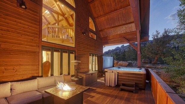 Uma cabana de madeira com hidromassagem, área de estar externa e lareira.