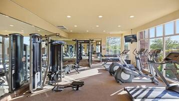 A gym with various exercise equipment, large windows, and a mirror.