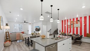 Une cuisine moderne dotée d’un îlot central, de luminaires suspendus et d’un coin repas avec des chaises et une table.