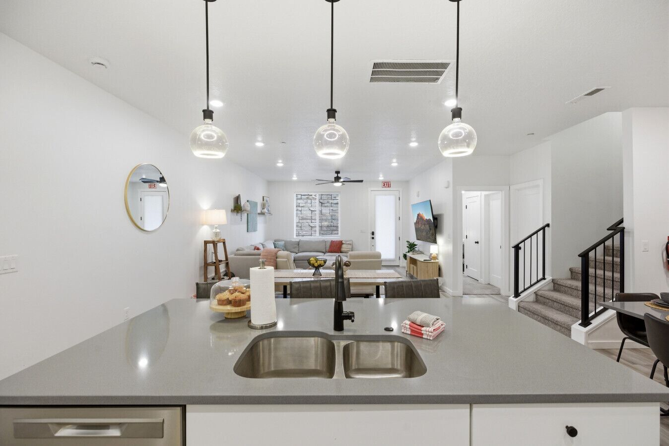 A modern kitchen with a central island, double sink, and pendant lighting.