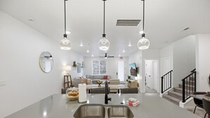 Une cuisine moderne dotée d’un îlot central, d’un évier double et de luminaires suspendus.