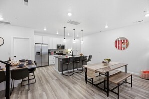 A modern kitchen with a central island, dining area with a bench, and a round wall decoration.