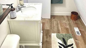 A bathroom with a white sink, a mirror, a towel rack, and a wooden floor.