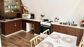 A compact kitchen with wooden cabinets, a microwave, a stove, and a dining table with placemats.