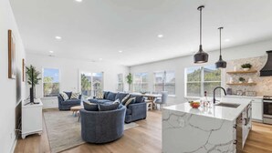 A spacious living area with a large sofa set, a kitchen with a marble island, and a dining area. - Casa Blanca Sol Luxe Sea View House w Pool (Surfside Beach)