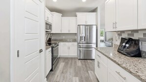 A modern kitchen with white cabinets, stainless steel appliances, and a granite countertop. - Salty Seagull Pet Friendly Beach House (Myrtle Beach)