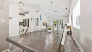 A spacious kitchen with modern appliances, a dining area with a long table, and a ceiling fan. - Salty Seagull Pet Friendly Beach House (Myrtle Beach)