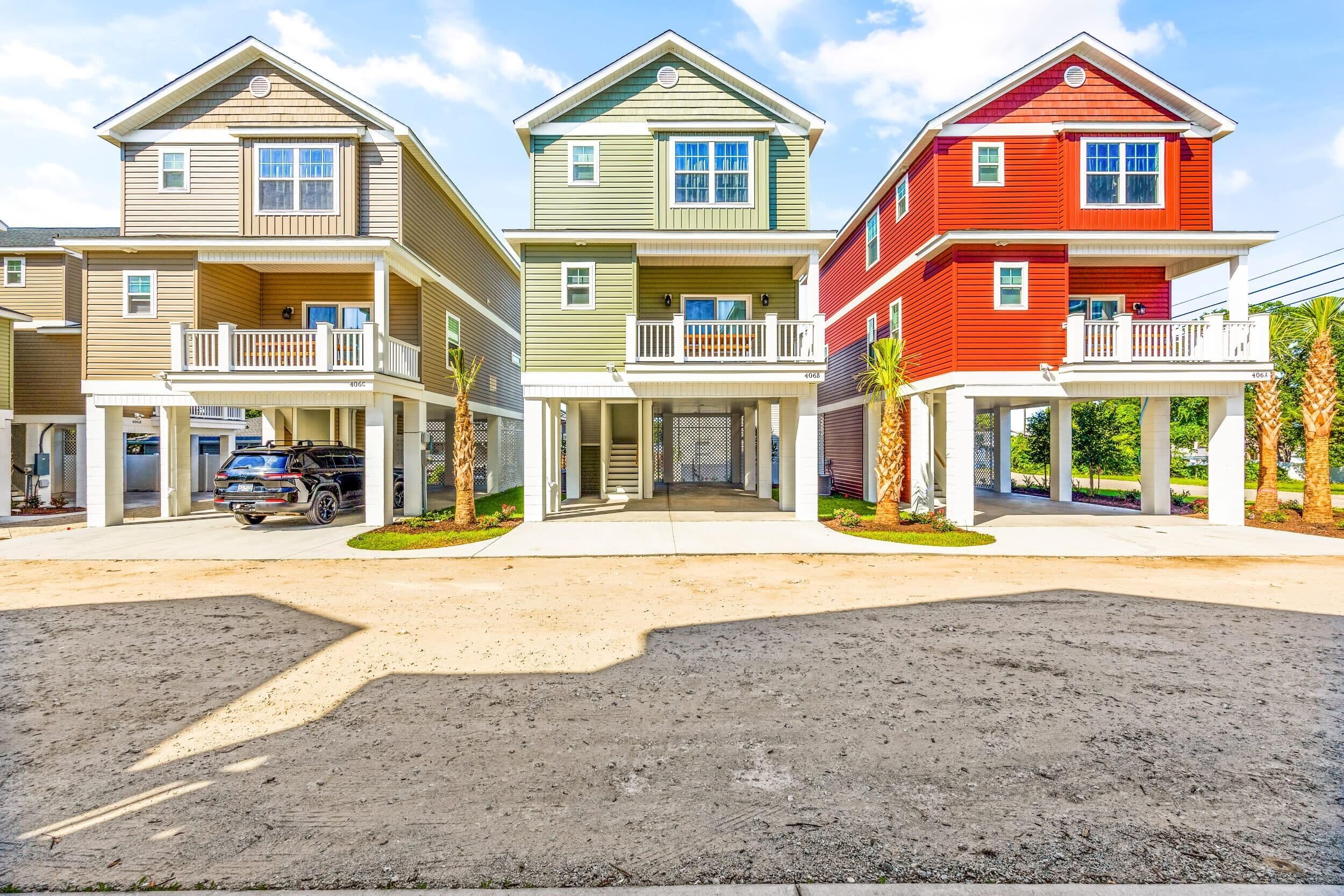 A row of three-story townhouses with balconies, a driveway, and a parked SUV.