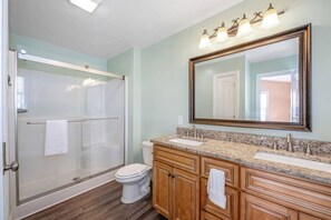 Une salle de bain avec une douche à parois de verre, des toilettes, un lavabo avec un meuble-vasque et un grand miroir.