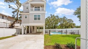 A two-story house with a covered patio, a swimming pool, and a fenced backyard.