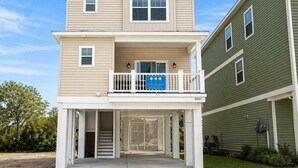 A two-story residential building with a balcony, a garage, and a visible address number. - Horizon Dune Pet Friendly House Walk to Beach (Myrtle Beach)